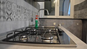 A kitchen with a gas stove, a faucet, and patterned tiles. - Casa dei Nonni (Genoa)