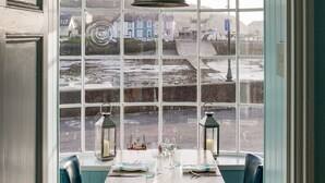 Un comedor con una mesa y sillas, un ventanal con vista a un pueblo y un techo decorativo.