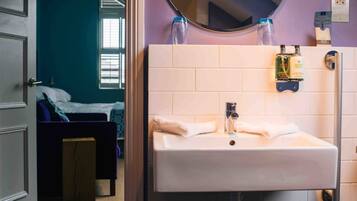 A bathroom with a white sink, a mirror, and toiletries on the wall.