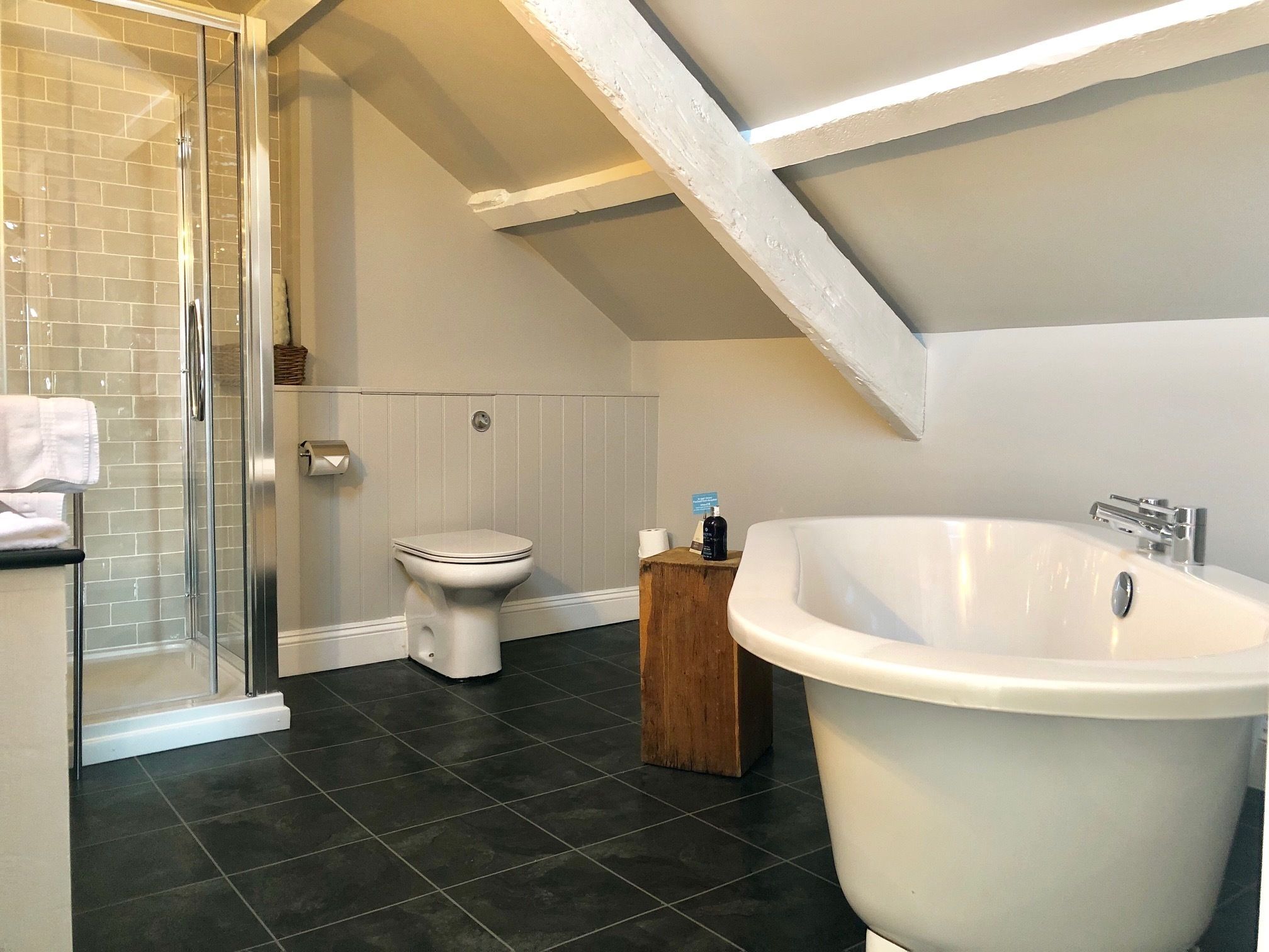 A modern bathroom with a glass shower enclosure, a white toilet, and a freestanding bathtub.