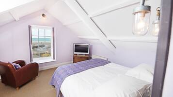 A bedroom with a bed, a TV, a window with a view, and a ceiling light fixture.