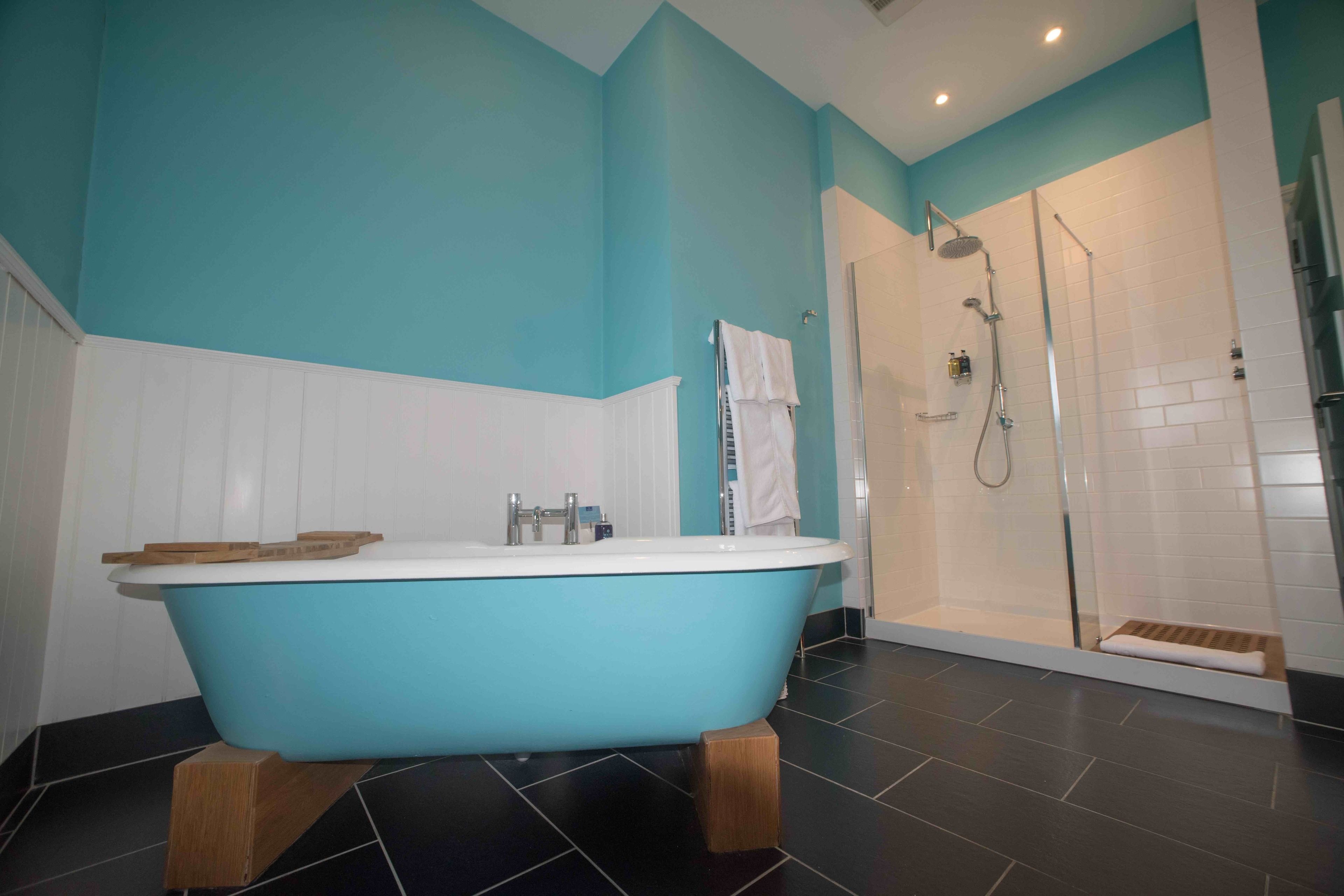 A bathroom with a freestanding bathtub, a shower area, and tiled flooring.