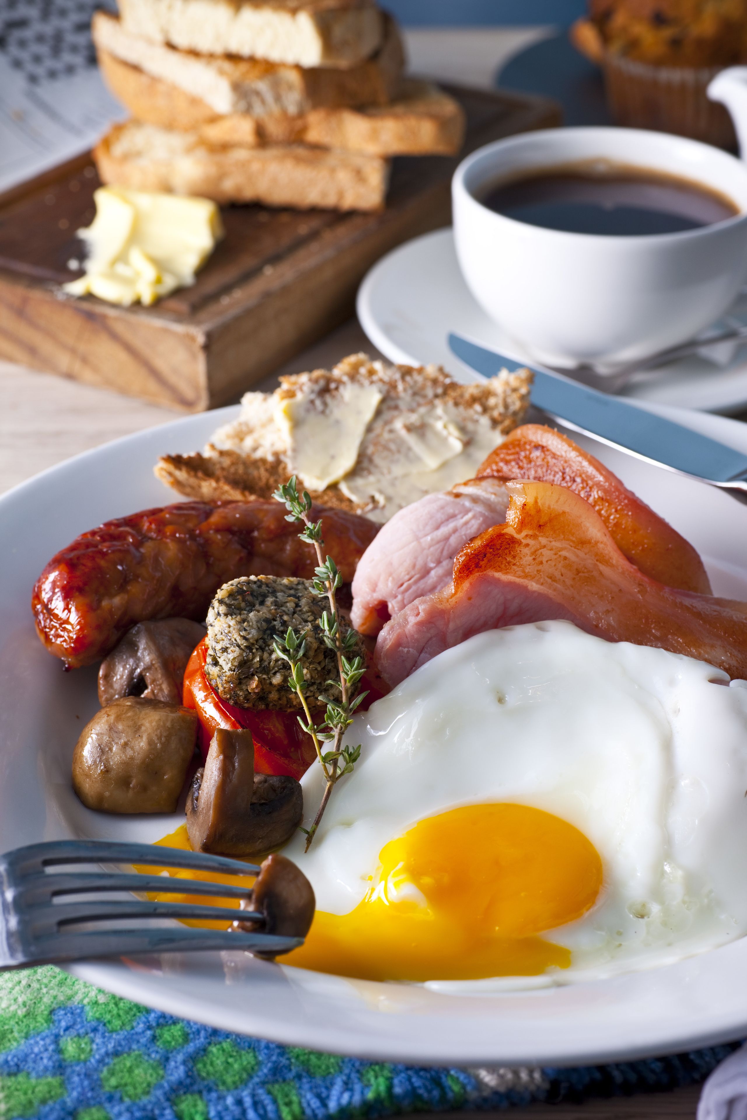 A breakfast plate with eggs, sausages, bacon, mushrooms, and toast.
