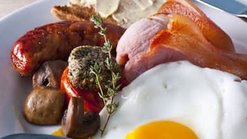 A breakfast plate with eggs, sausages, bacon, mushrooms, and toast.