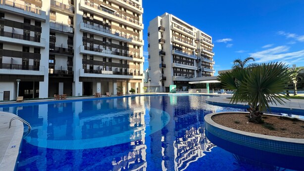 A modern hotel with multiple balconies, a swimming pool, and a clear blue sky. - Venice Park Hplus Long Stay (Guará)