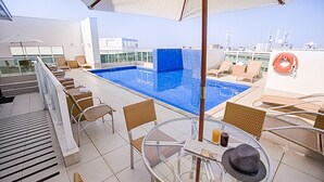A rooftop pool area with lounge chairs and a table with drinks. - Biarritz Hplus Long Stay (Brasília)