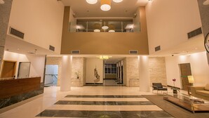 A spacious lobby with a reception desk, seating area, and a staircase leading to an upper level. - Biarritz Hplus Long Stay (Brasília)