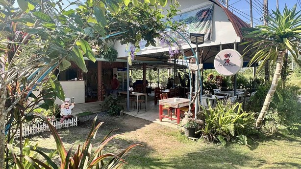 A house with a covered outdoor area, a sign for 'Lee Red House', and a fenced garden. - Lee Red House (Ko Kood)