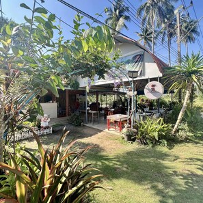 A house with a covered outdoor area, a sign for 'Lee Red House', and a fenced garden.