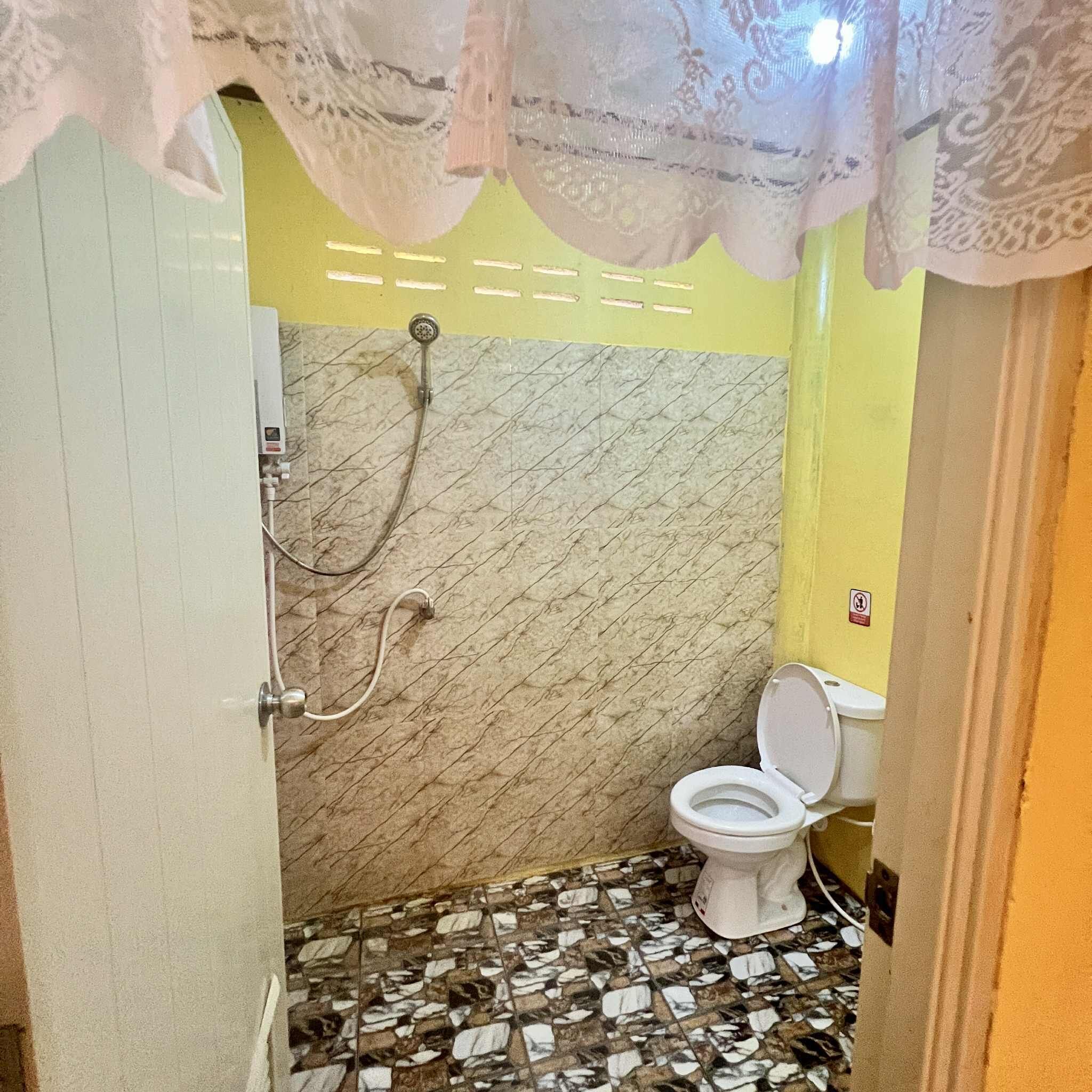 Une salle de bain avec des toilettes, une douche et un sol carrelé.