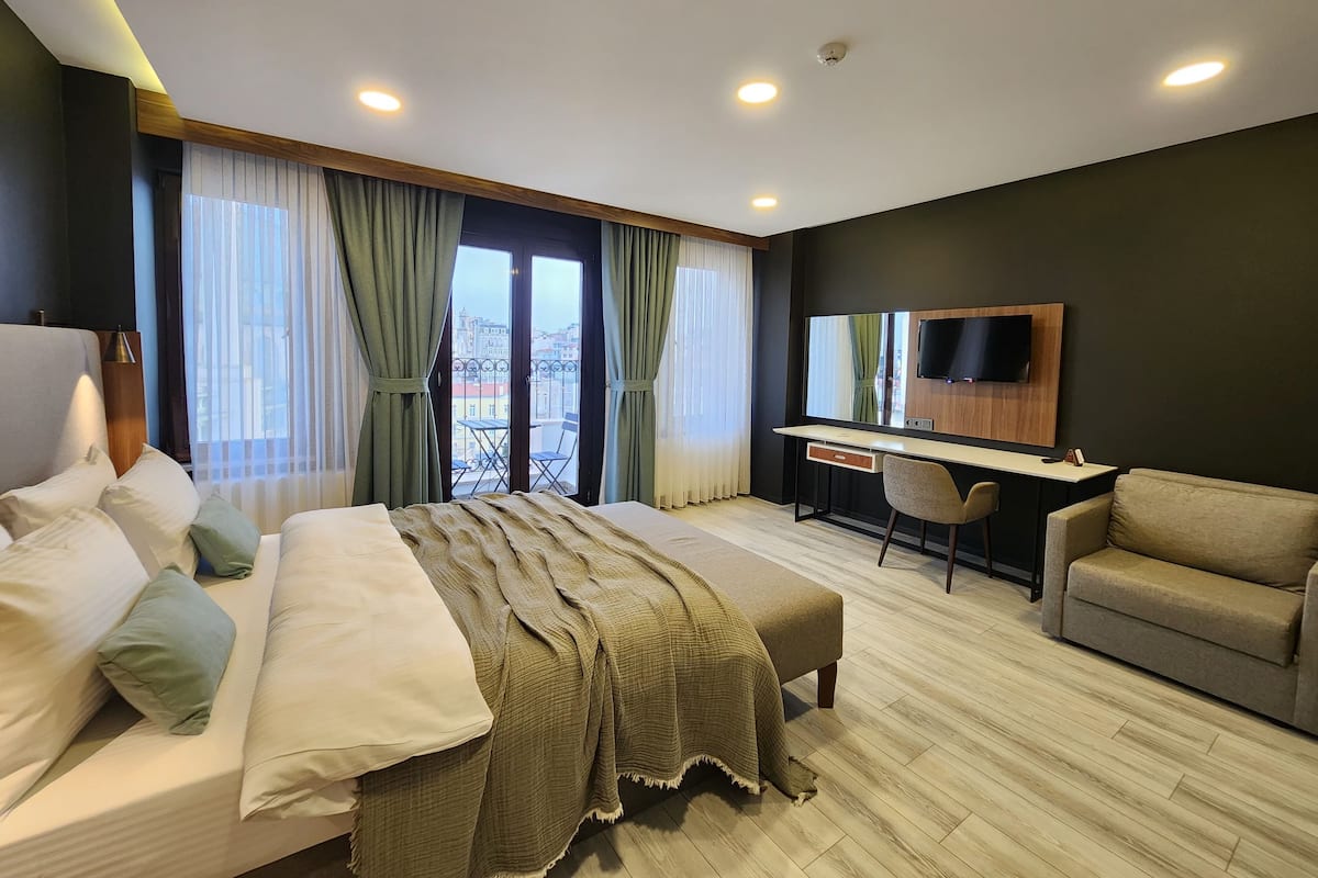A modern hotel room with a bed, a desk, a chair, and a TV.