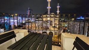 Vista de una mezquita con dos minaretes, una cúpula grande y un patio con bancos.