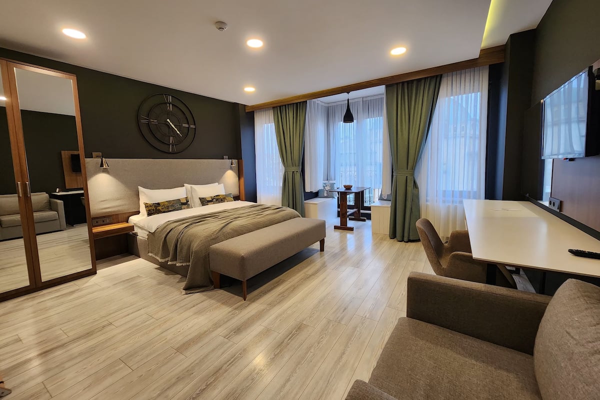 A modern hotel room with a large bed, a desk, and a seating area.