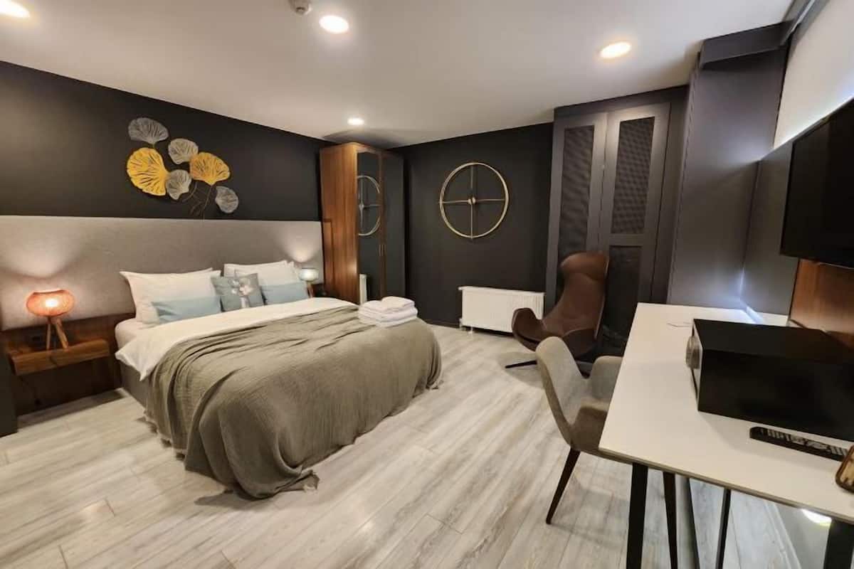 A modern bedroom with a bed, bedside table, lamp, and a TV on a desk.
