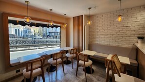 Un restaurante con vistas a un canal, muebles de madera y lámparas colgantes.