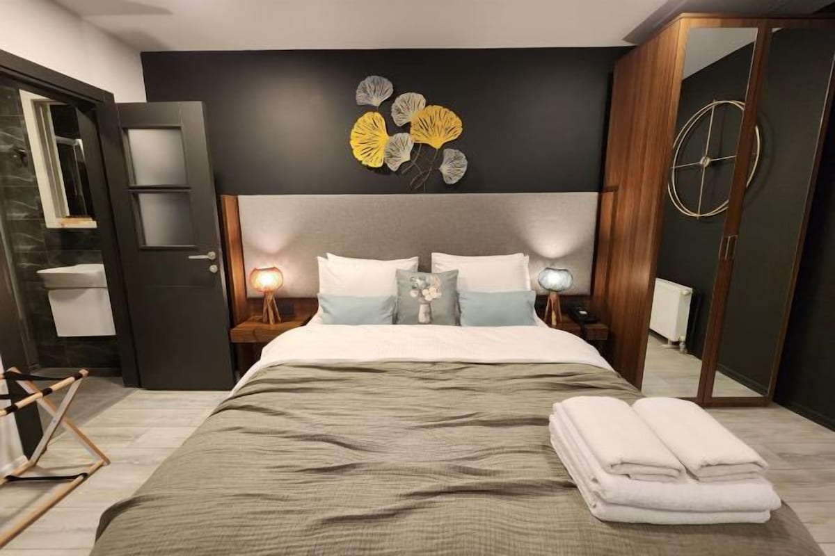 Un dormitorio moderno con una cama, mesitas de noche, un espejo y una obra de arte en la pared.