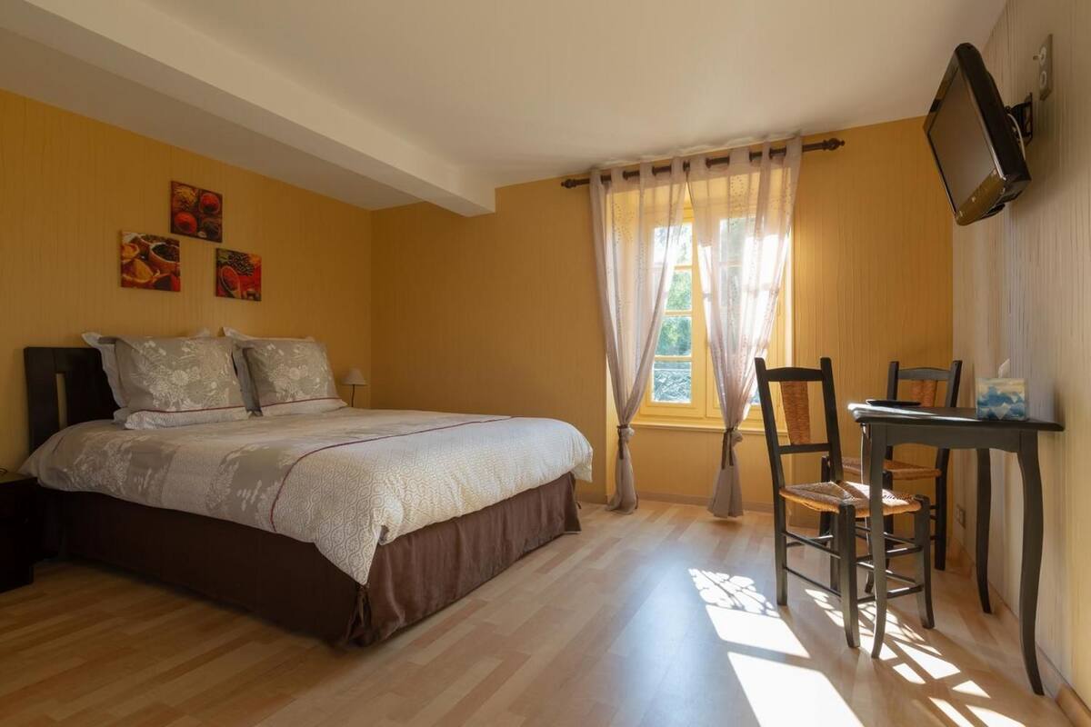 Een slaapkamer met een bed, bureau en televisie.