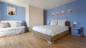 Een slaapkamer met een bed, een slaapbank en een nachtkastje.