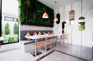 Uma área de jantar moderna com parede verde, mesa branca e cadeiras de cobre.