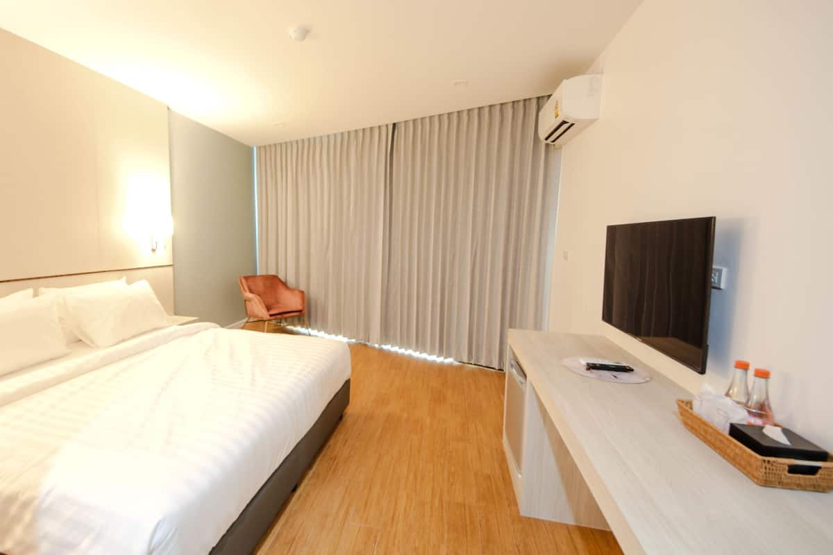 A hotel room with a large bed, a desk with a TV, and a chair.