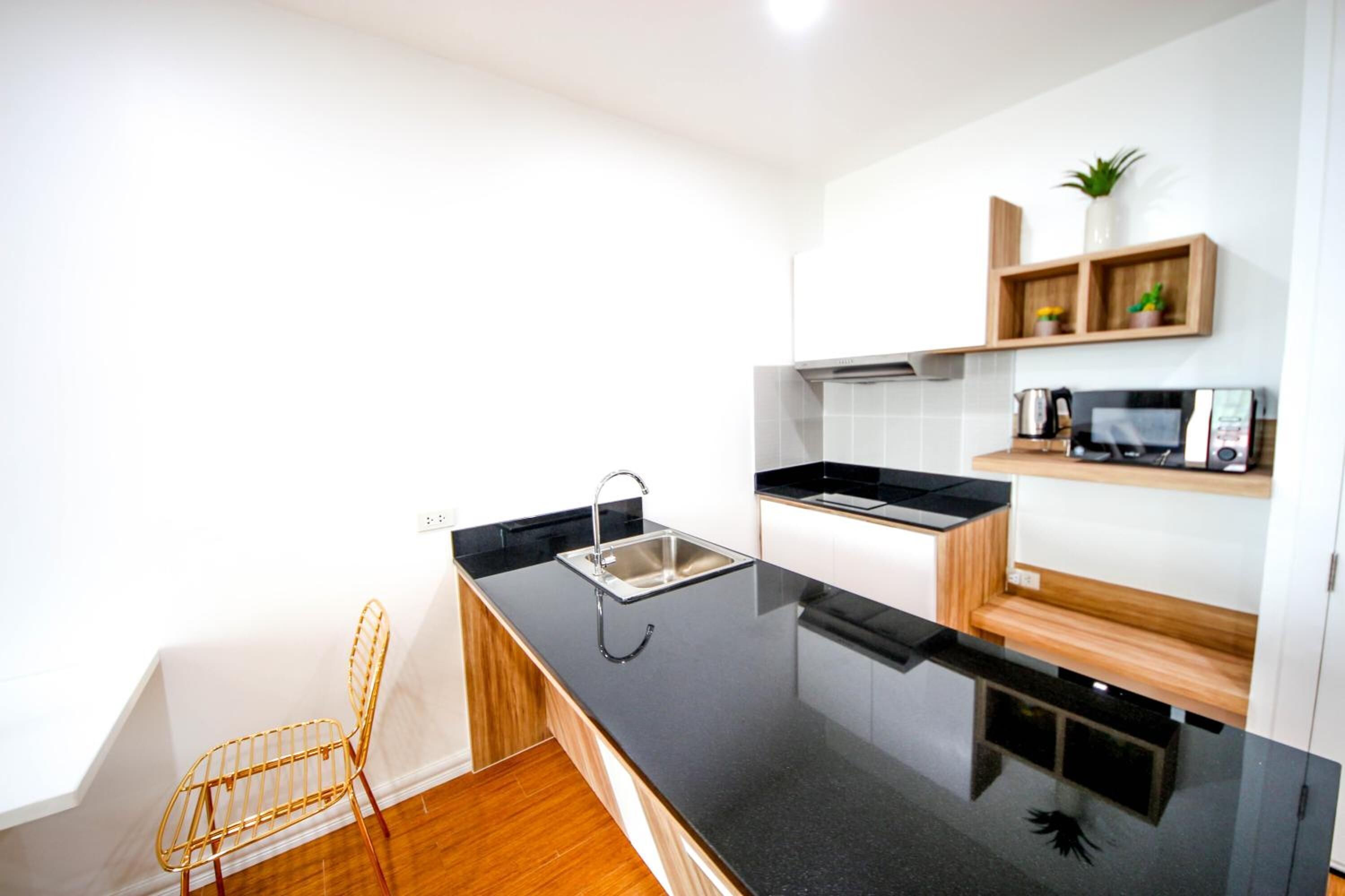 A modern kitchen with a black countertop, stainless steel sink, and wooden shelves.