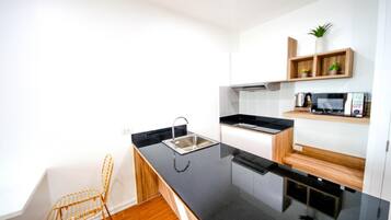 A modern kitchen with a black countertop, stainless steel sink, and wooden shelves.