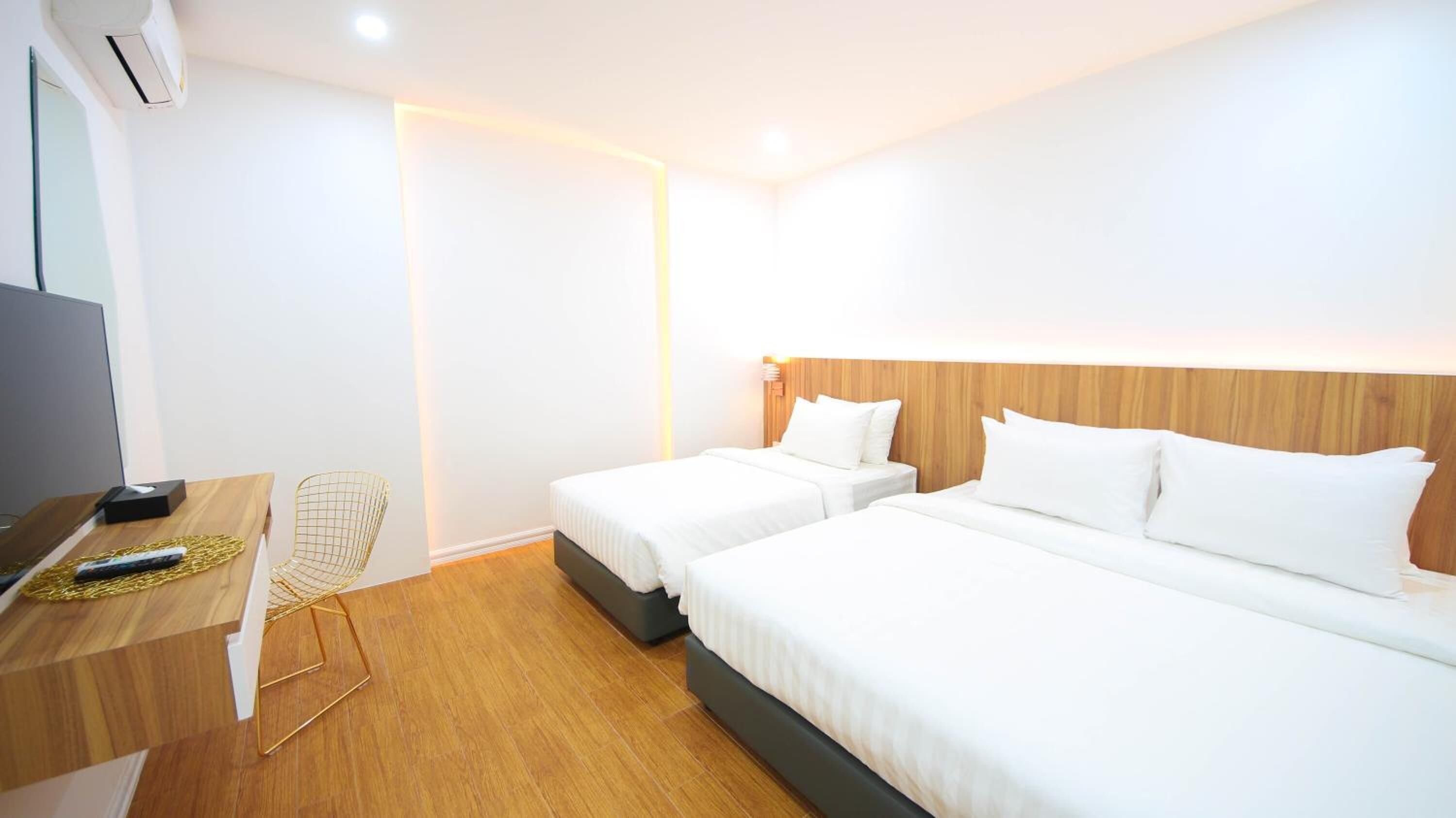 A hotel room with two single beds, a wooden desk with a chair, and a TV.