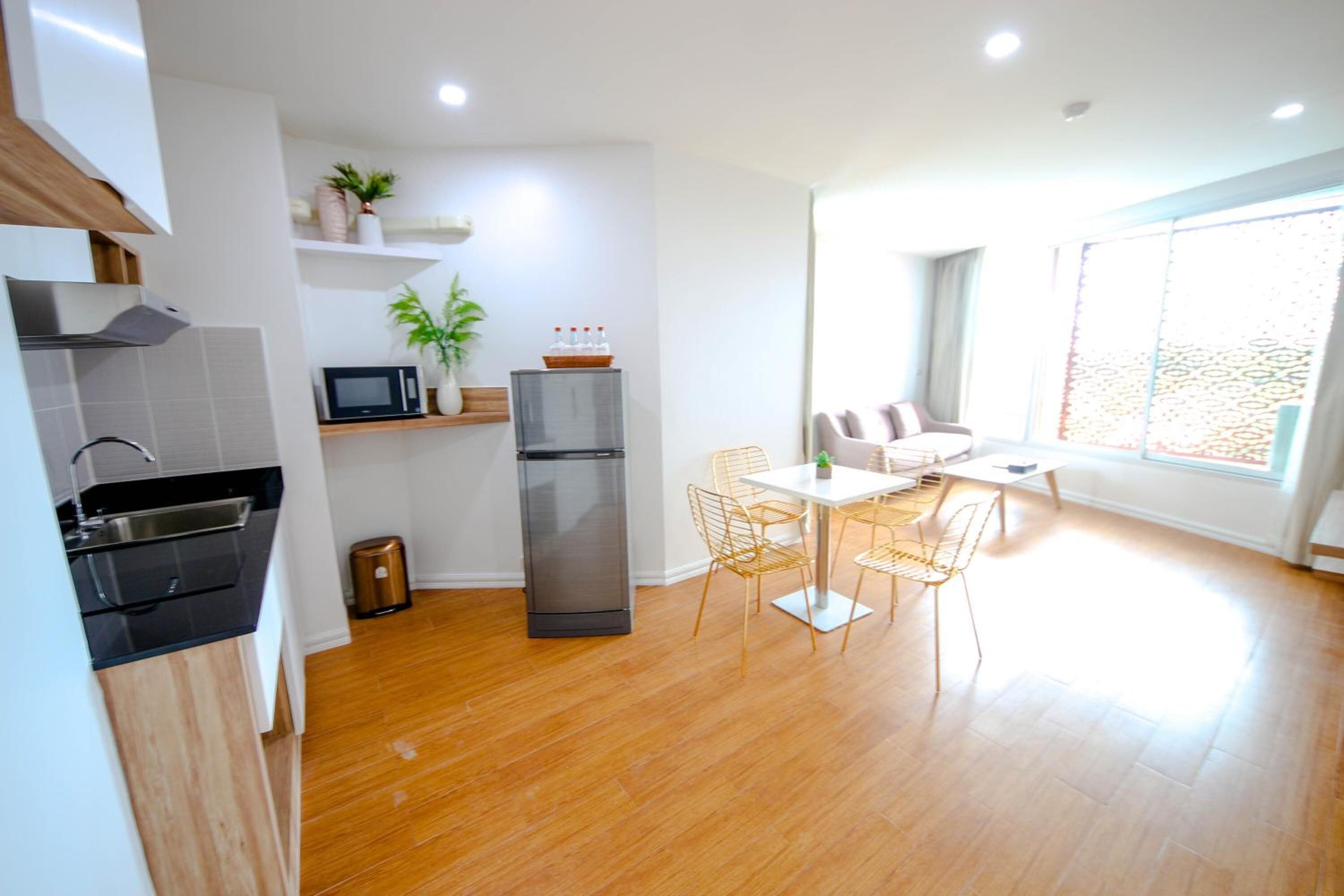 A modern kitchen with a microwave, refrigerator, and sink. There is a dining area with a table and chairs.