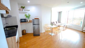 A modern kitchen with a microwave, refrigerator, and sink. There is a dining area with a table and chairs.