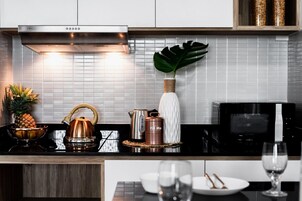 Una cocina moderna con una campana extractora de acero inoxidable, un microondas y una cafetera en la encimera.