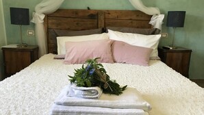 Una cama bien hecha con sábanas blancas, un ramo de flores y una pila de toallas.