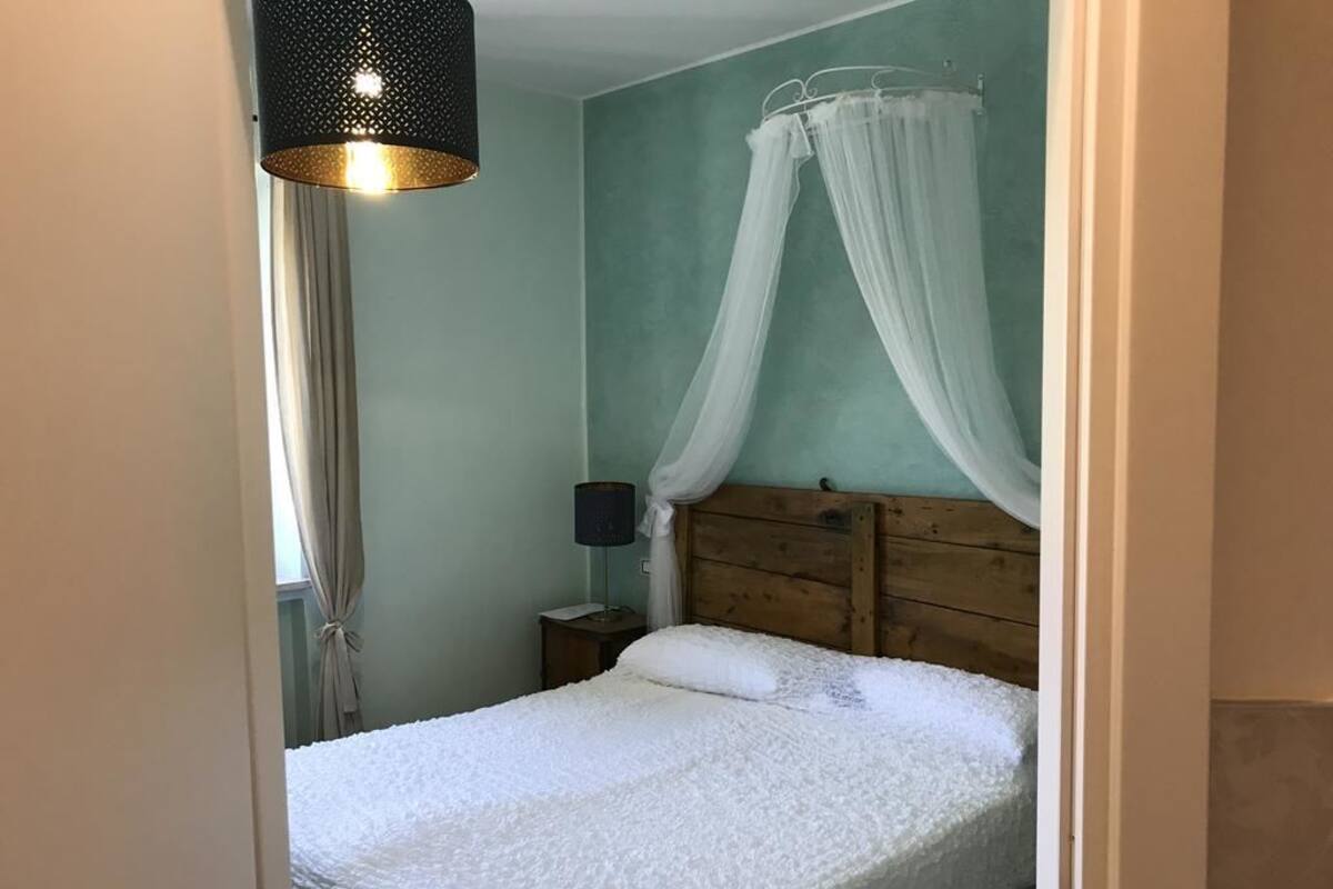 A bedroom with a wooden headboard, a canopy bed, a bedside lamp, and a curtain.
