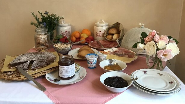 Una mesa con diversos alimentos, como pan, frutas y frascos de conservas.