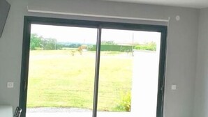 A room with a large sliding glass door leading to a grassy outdoor area. - Le Temps d'un Reve (Eauze)