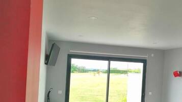 Quarto com uma grande porta de correr de vidro que dá para uma área externa gramada.