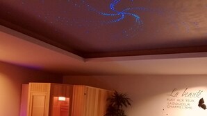 A spa room with a hot tub, wooden paneling, a potted plant, and a wall with a decorative phrase. - Le Temps d'un Reve (Eauze)