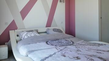 A bedroom with a bed, pillows, and a patterned bedspread.