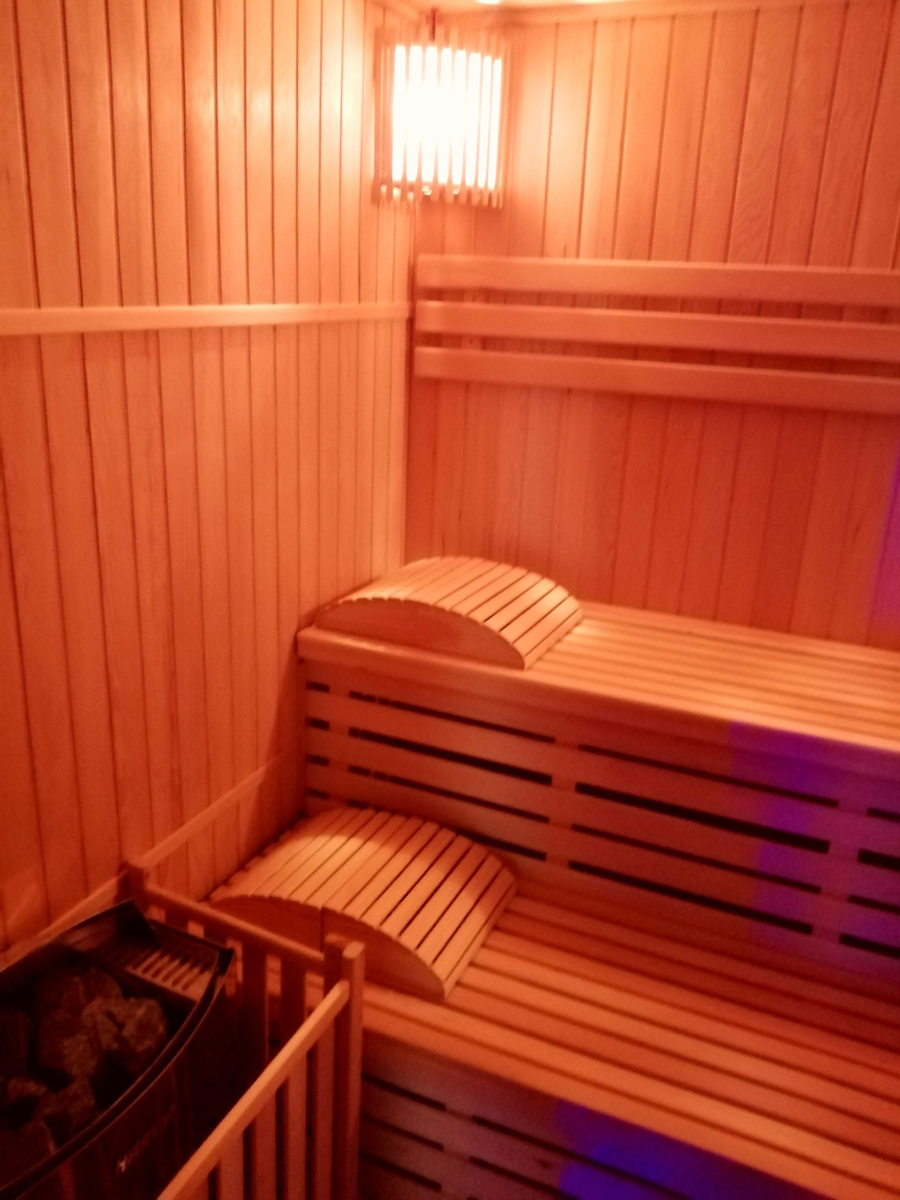 Een sauna met houten banken en een bank met een gebogen rugleuning.