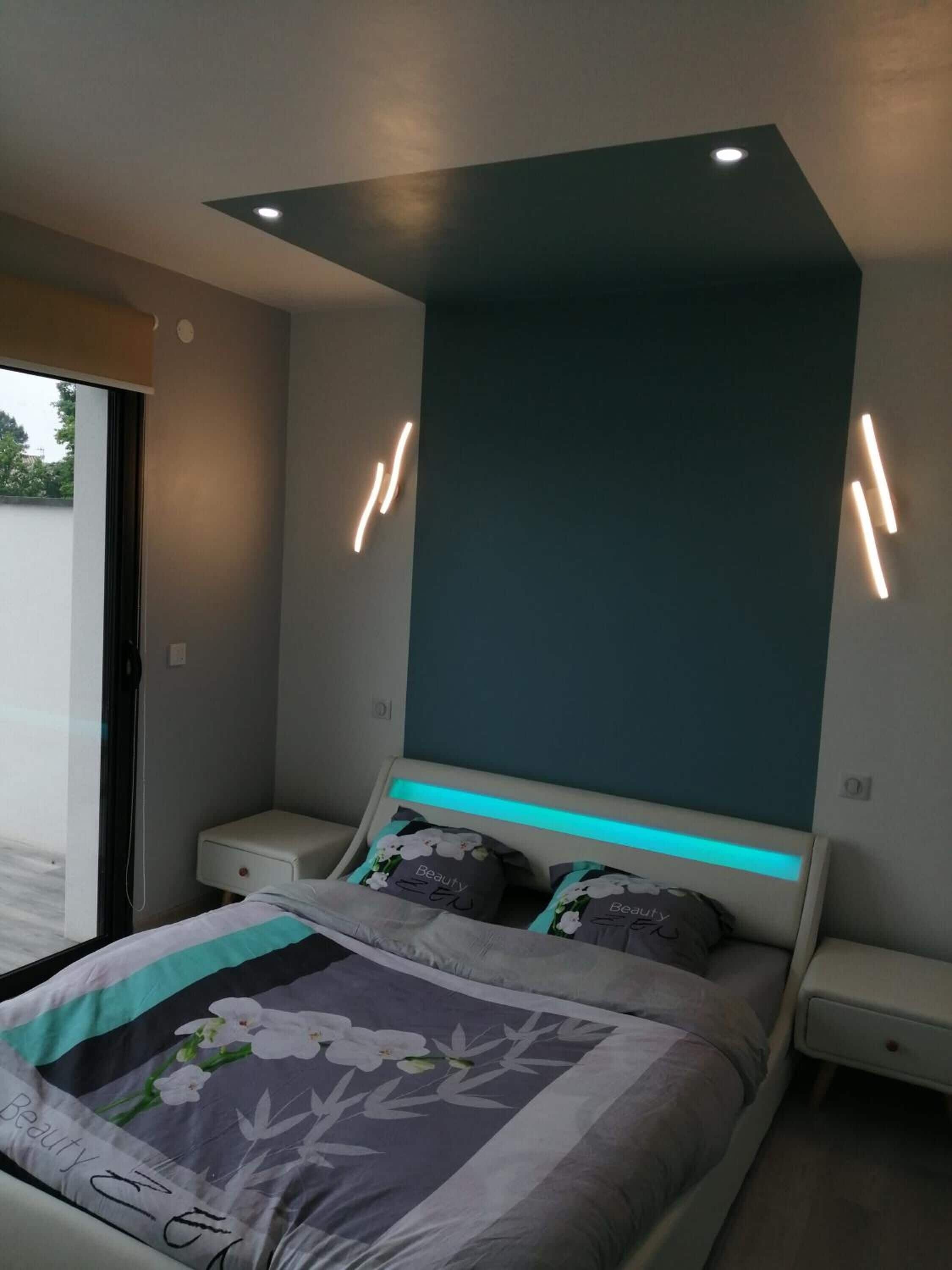 Un dormitorio moderno con cama, mesitas de noche y lámpara en el techo.