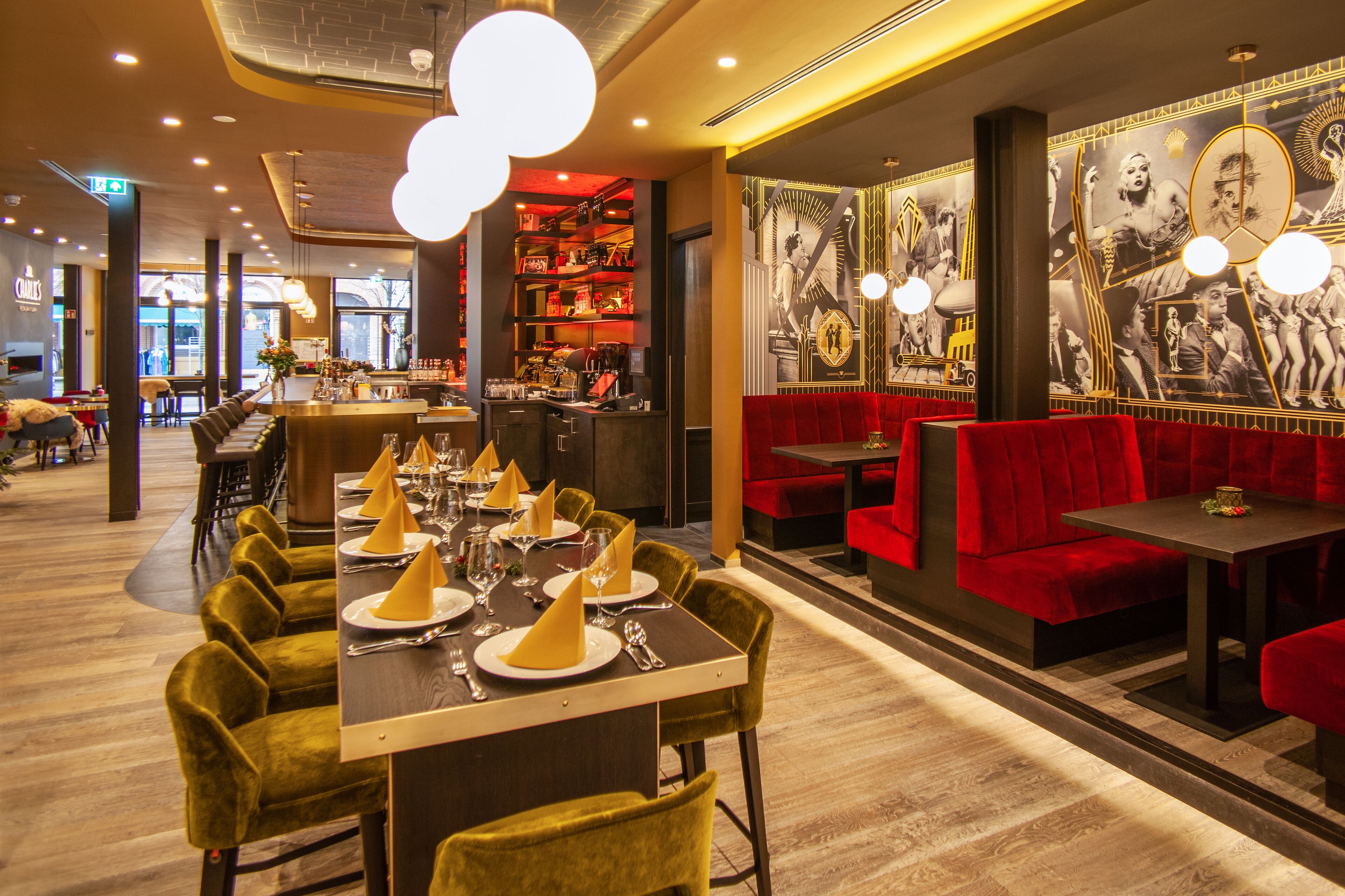 Een restaurant met een lange tafel gedekt voor een maaltijd, rode bekleden zitbanken en een bar.