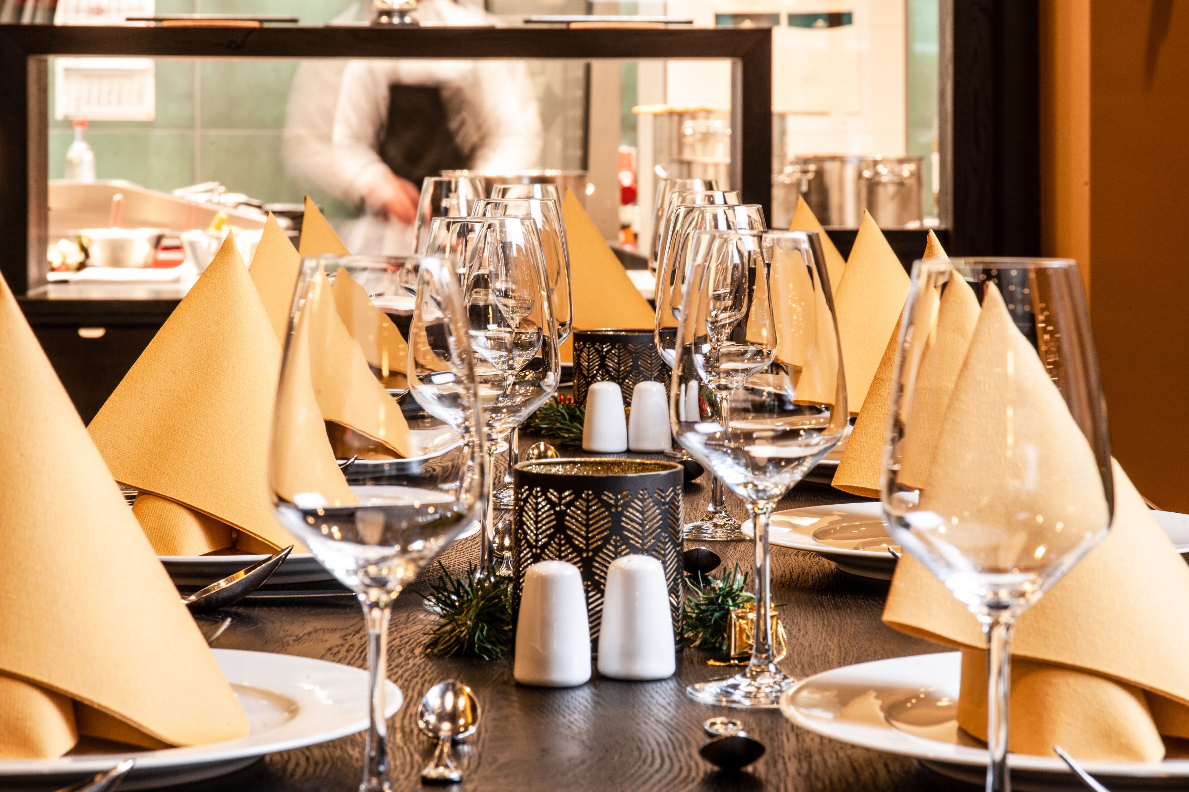 A dining table set with multiple wine glasses, napkins, and salt shakers.