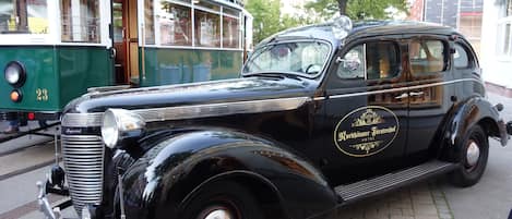 A vintage black car parked on a cobblestone street.