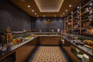 A breakfast buffet area with a variety of food and drink options, a decorative ceiling, and a sign reading "CHARLIE'S Nordhäuser Fürstenhof".