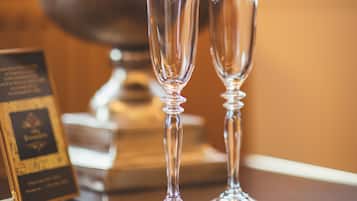 Two champagne flutes on a table with a large metal bucket labeled "Champagne" in the background.