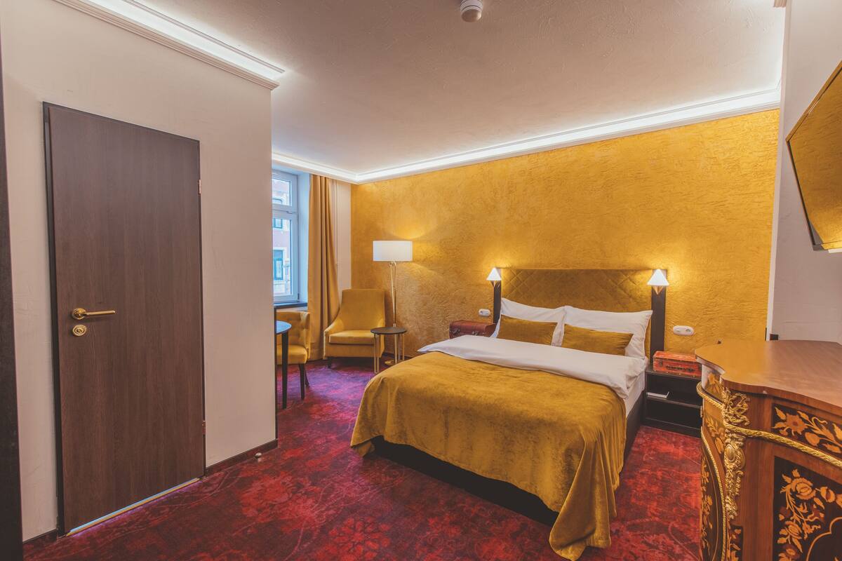Une chambre d’hôtel avec un lit, un bureau, une chaise et une fenêtre.