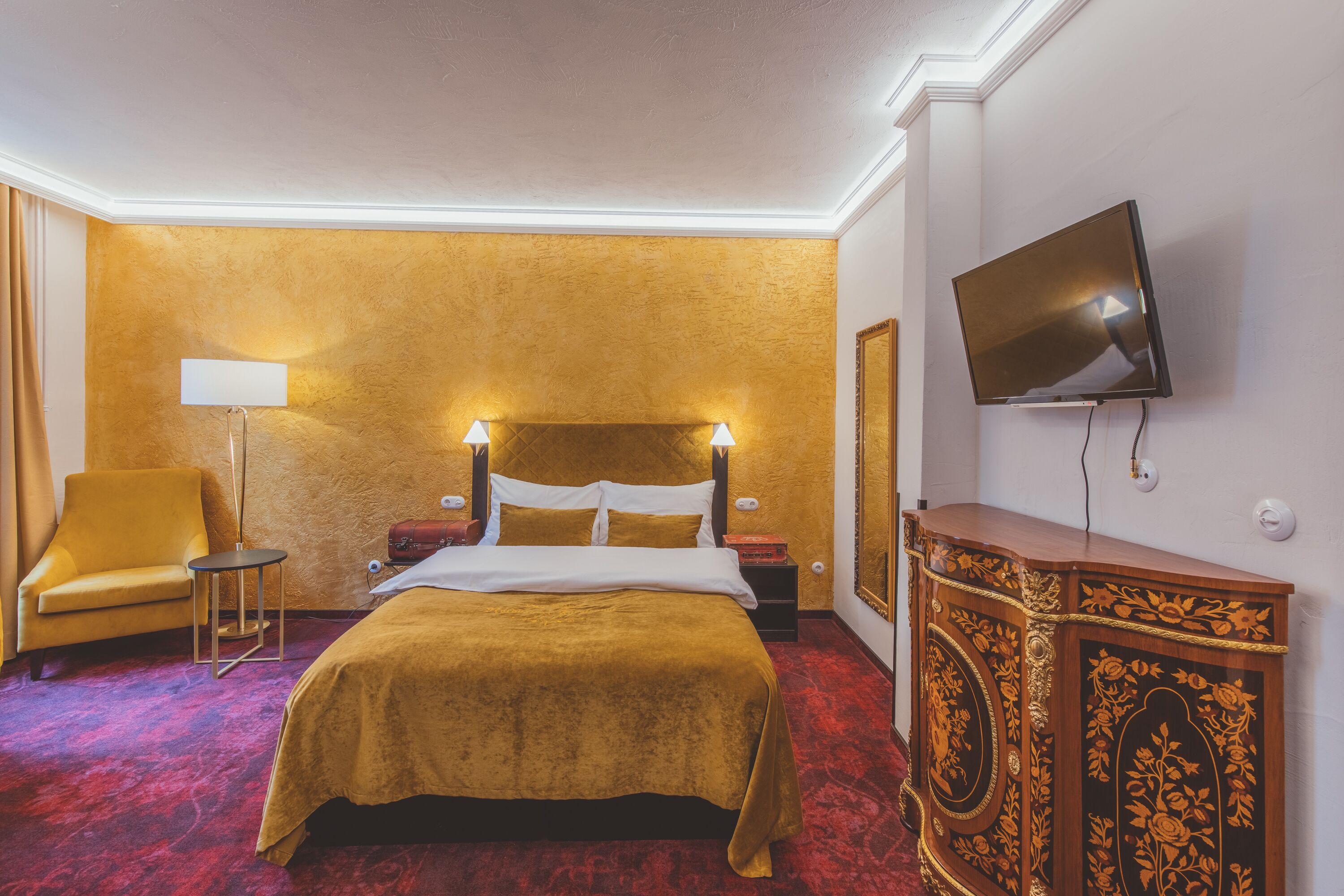 Une chambre d’hôtel avec un grand lit, une télévision, une table de chevet, une lampe et un meuble décoratif.