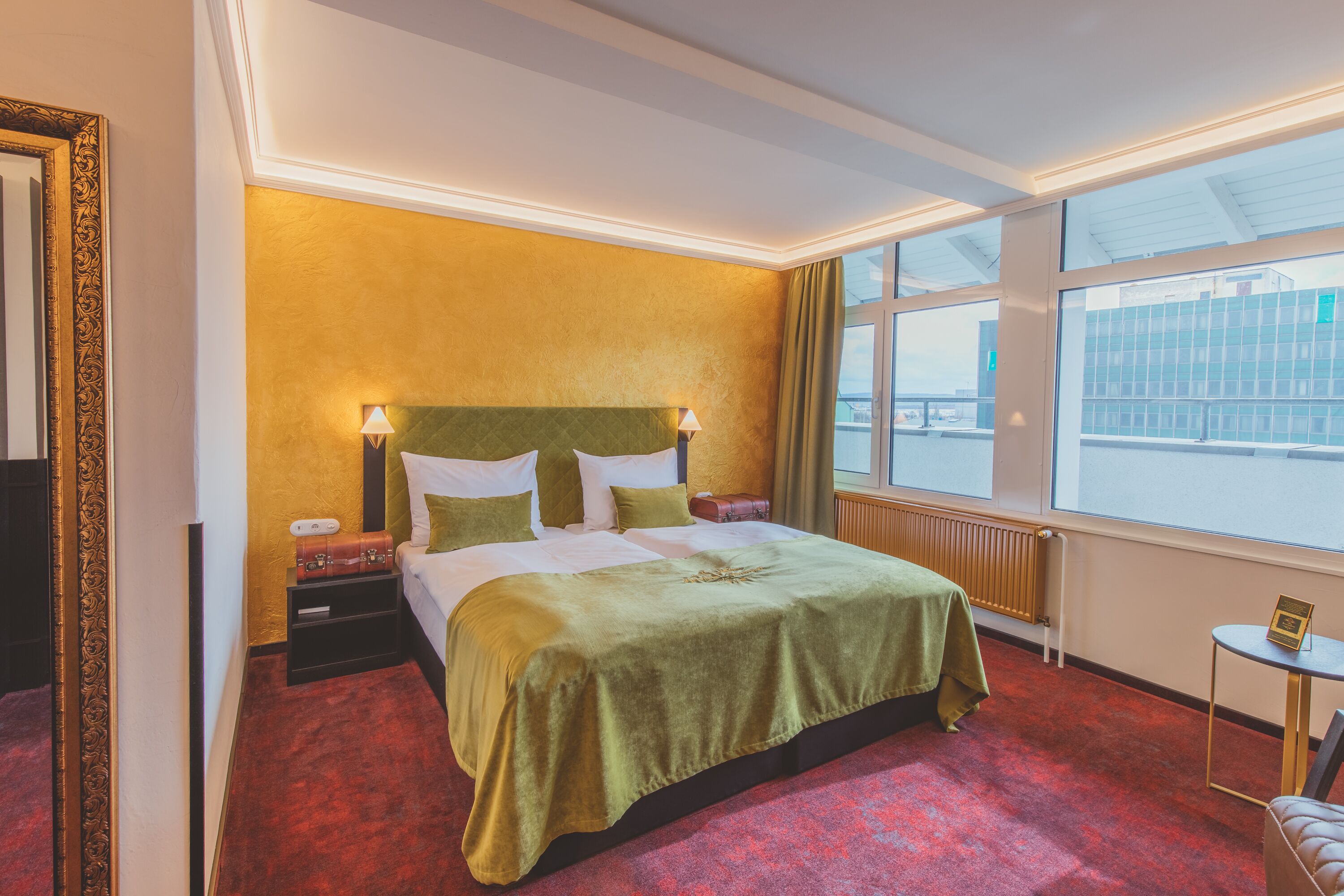 Ein Hotelzimmer mit einem großen Bett, zwei Nachttischen, einem Fenster mit Blick und einem kleinen Tisch mit einer Lampe.