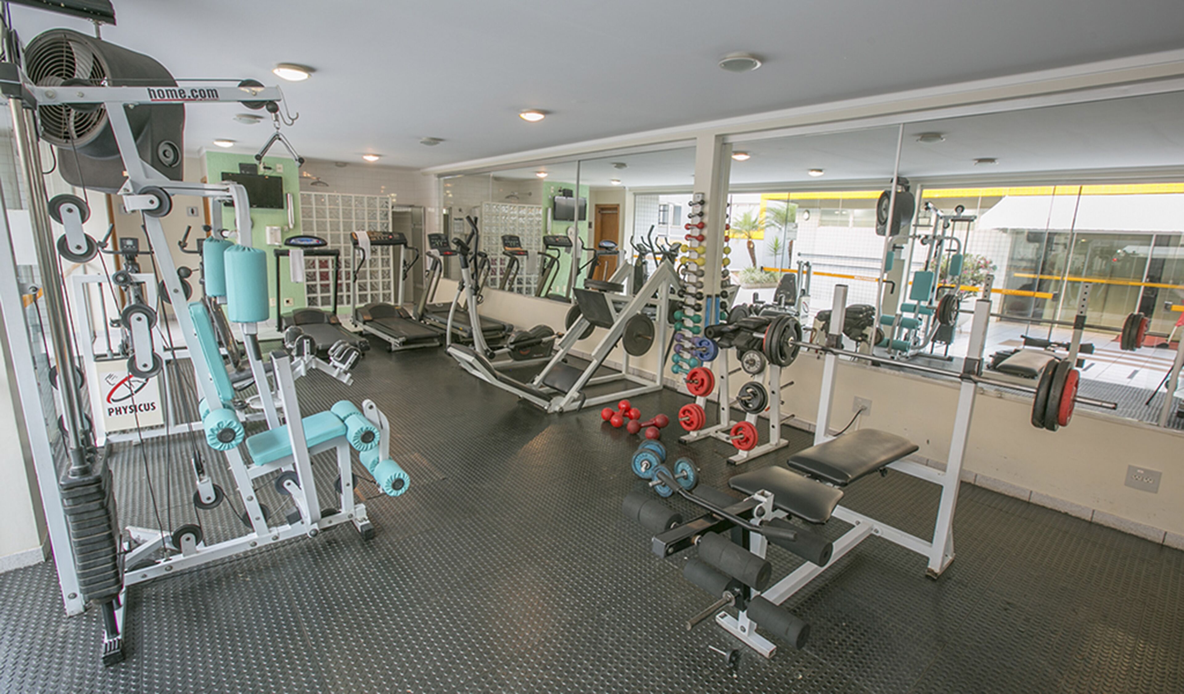 A gym with various exercise equipment, including treadmills, weight machines, and free weights.
