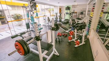 Une salle de sport équipée de divers appareils d’entraînement, notamment des machines à poids et des poids libres.