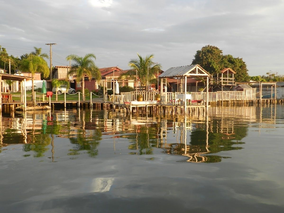 A waterfront property with multiple wooden structures, including a covered area and a dining setup.